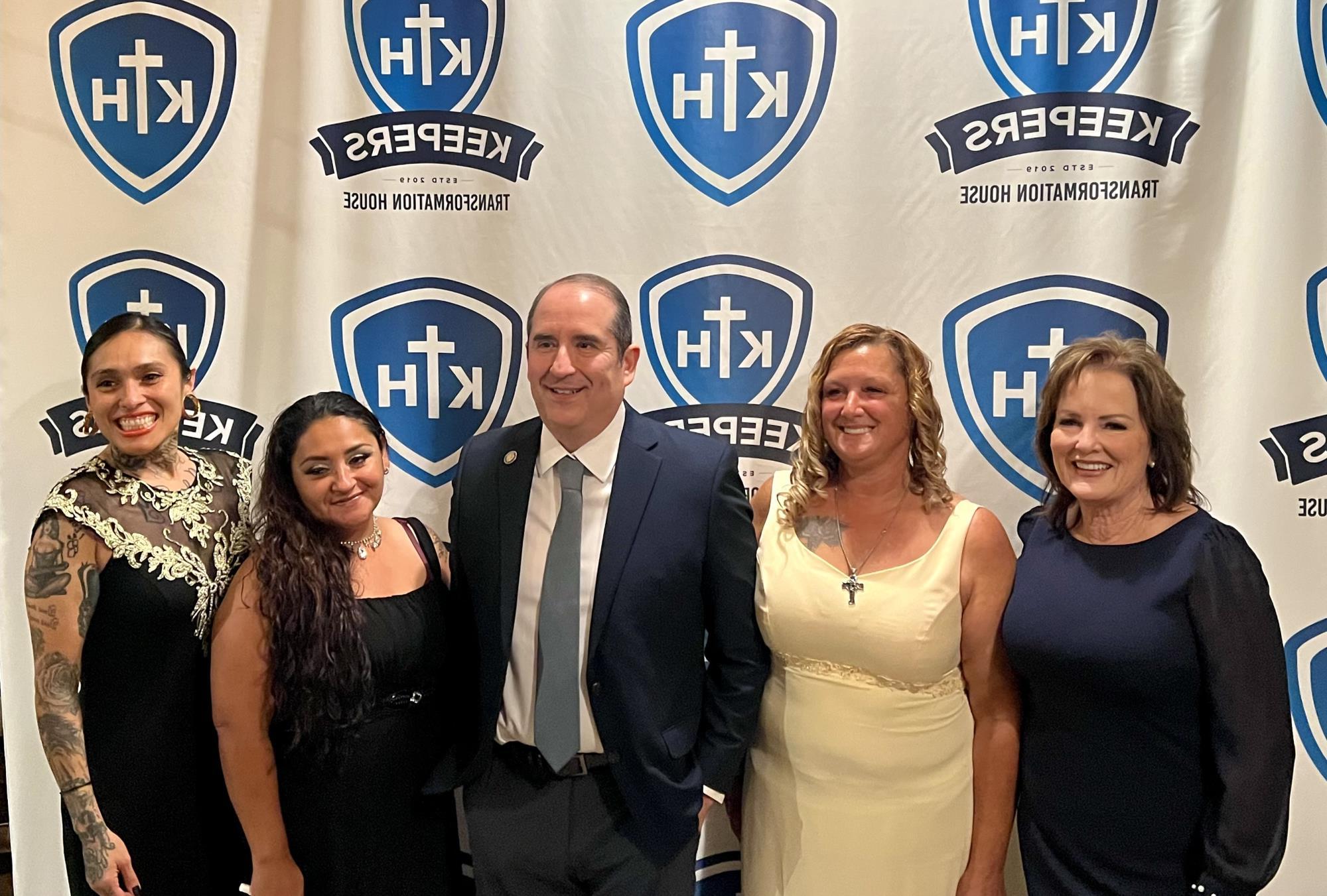 District 3 Supervisor Jeff Flores standing with several women in front of a Keeper's Transformation House backdrop.